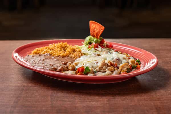Grilled chicken fajita mix topped with melted cheese, served with Mexican rice, refried beans, and a guacamole salad garnished with a tortilla chip.