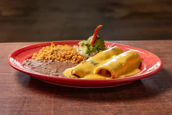 Cheese-smothered enchiladas served with refried beans, seasoned rice, and a guacamole-topped salad on a red Mexican-style dinner plate.