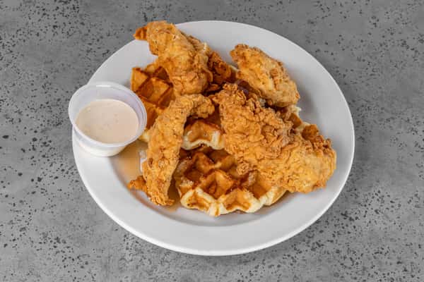 Golden fried chicken tenders served atop fluffy Belgian waffles with a side of creamy dipping sauce — a sweet and savory Southern comfort classic.