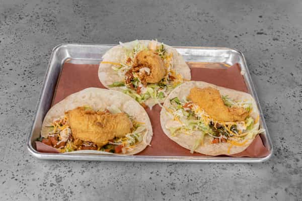 Trio of soft-shell tacos filled with crispy fried chicken, shredded lettuce, cheese, and diced tomatoes — perfect for Tex-Mex or fusion street food marketing.