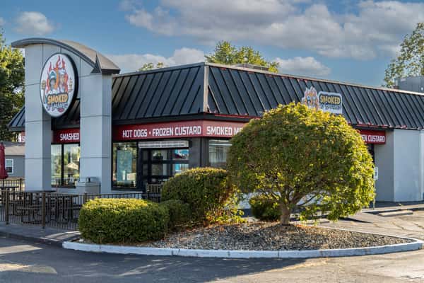 Exterior of Smoked N' Smashed restaurant featuring bold signage promoting hot dogs, frozen custard, and smoked meats — ideal for local business listings and food tourism.