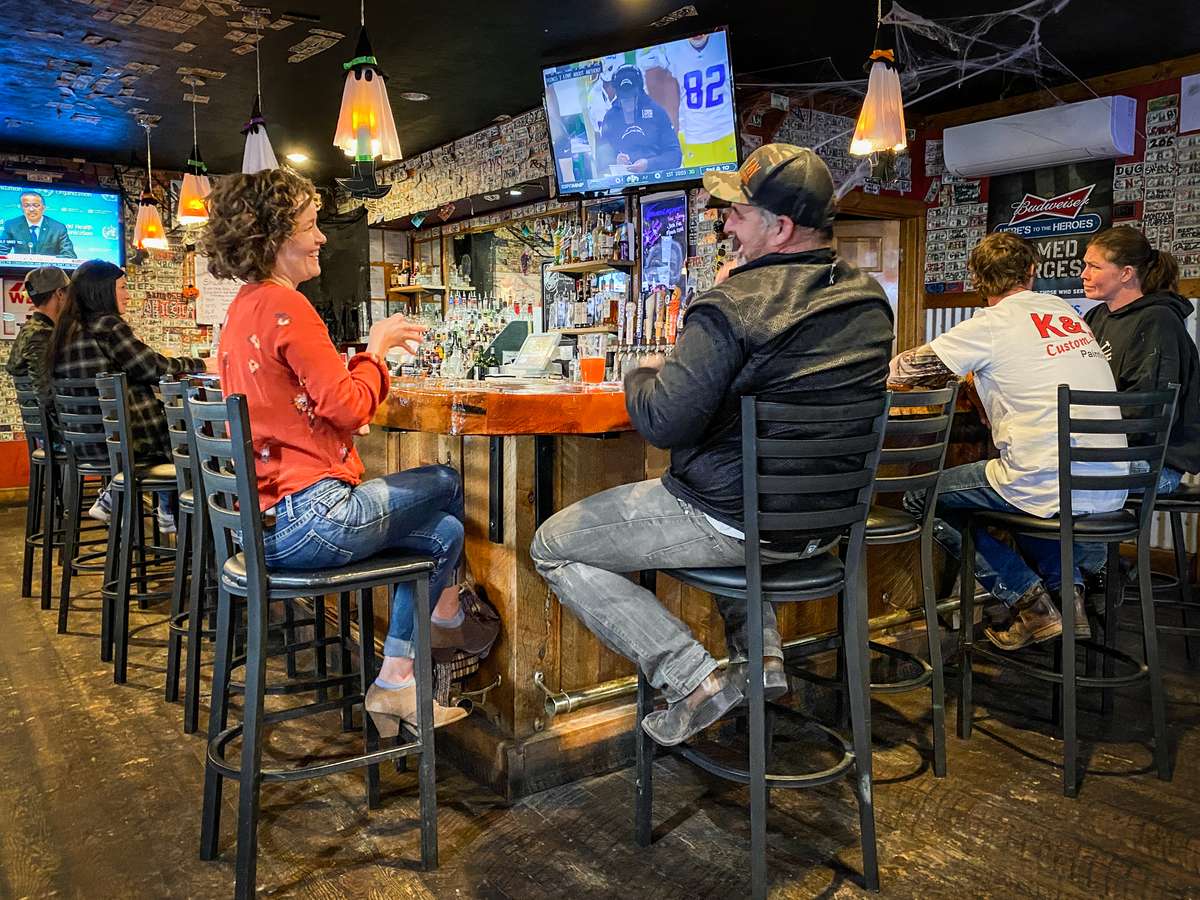 Patrons sitting around a bar enjoying beer and sports