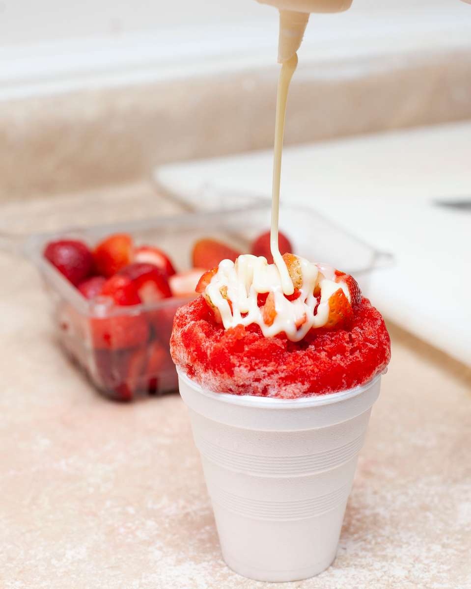 drizzle being poured on a red snowcone