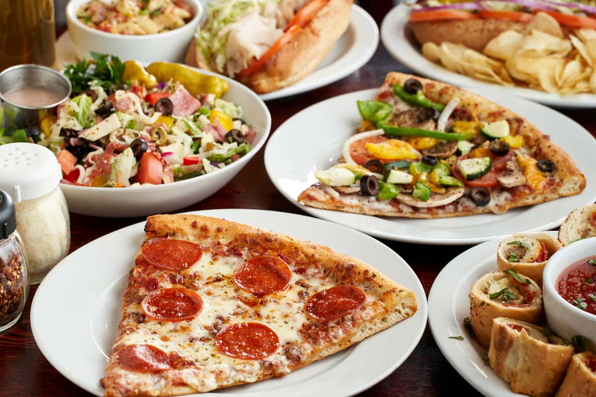 Slices of pizza of different types paired with salads and appetizers