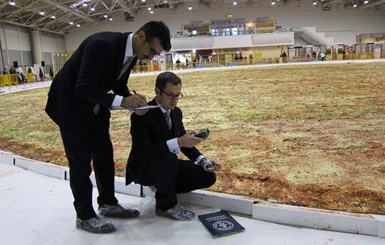 Two judges measuring the size of the world's biggest pizza