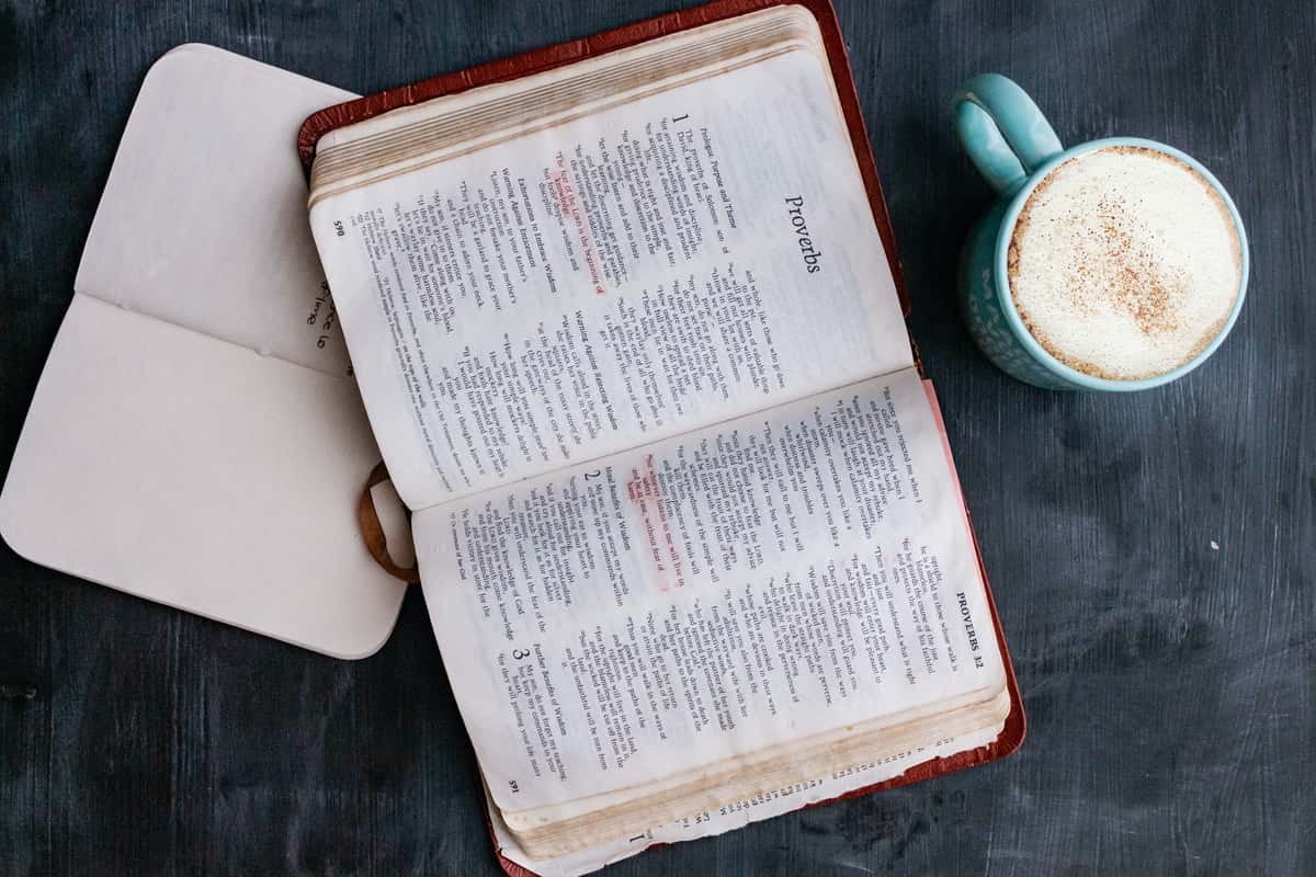 Bible open to Proverbs with a mug of coffee