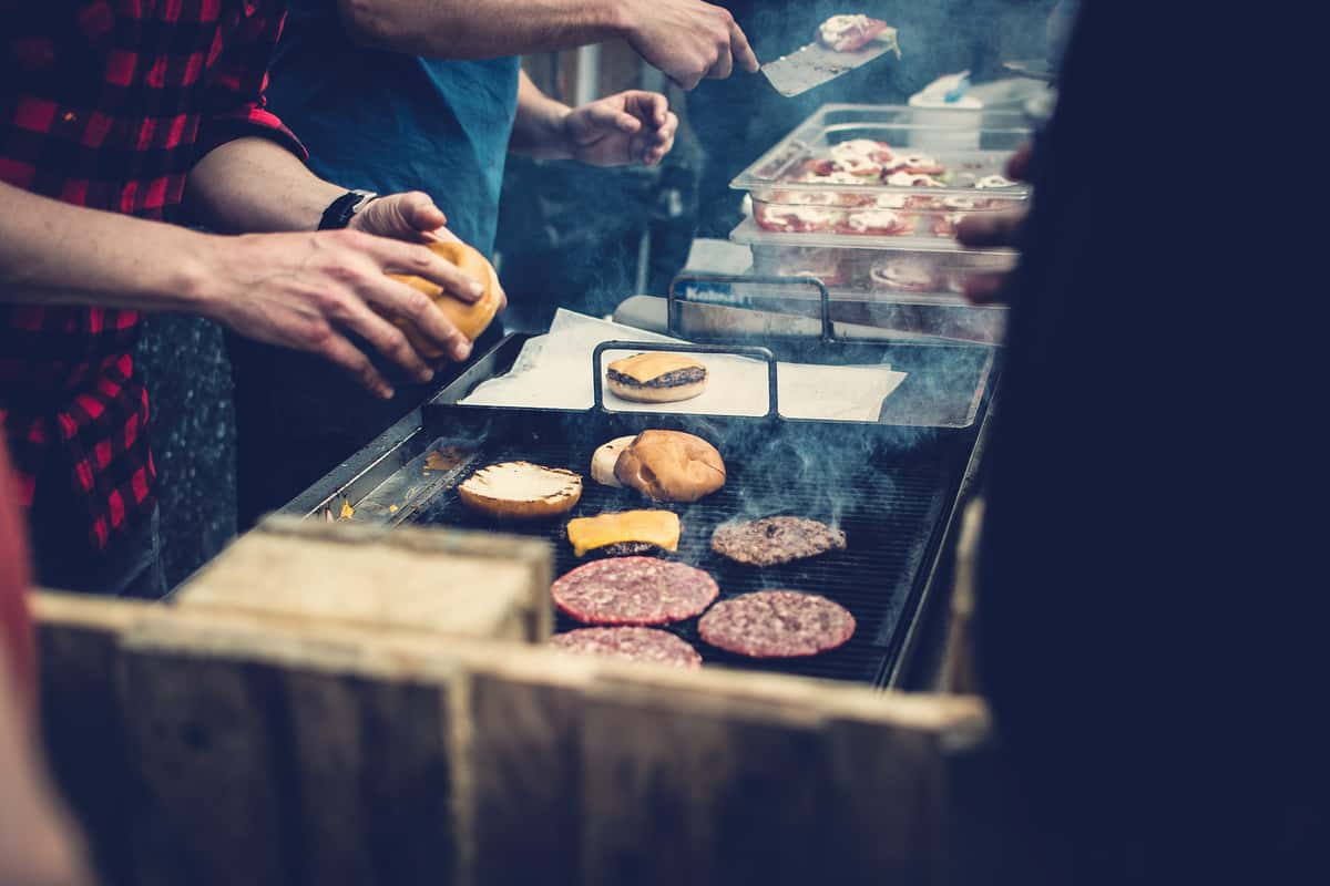 person making burgers on grill