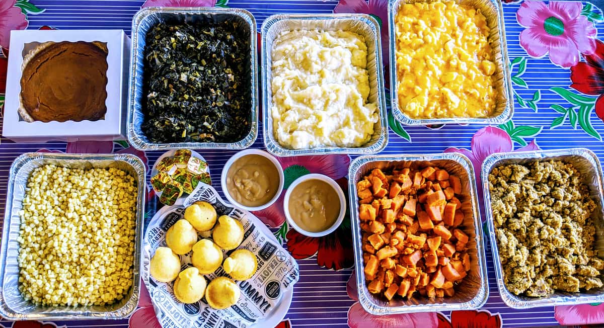Table of corn, mashed potatoes, gravy, collard greens, candied yams, cornbread muffins, sweet potato pie, mac & cheese, cornbread dressing
