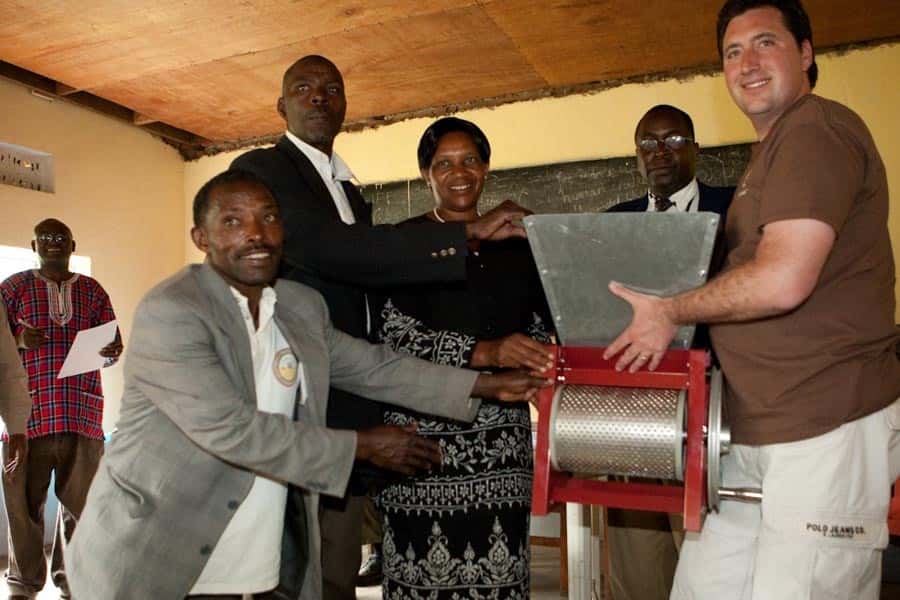 Shallom Berkman, at right, holds a coffee pulp grinder with four farmers of the Mountain Gorilla Coffee Estate in Uganda