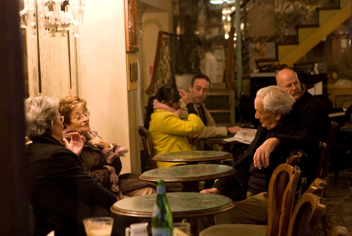 People chat around tables outside a Venice, Italy cafe.