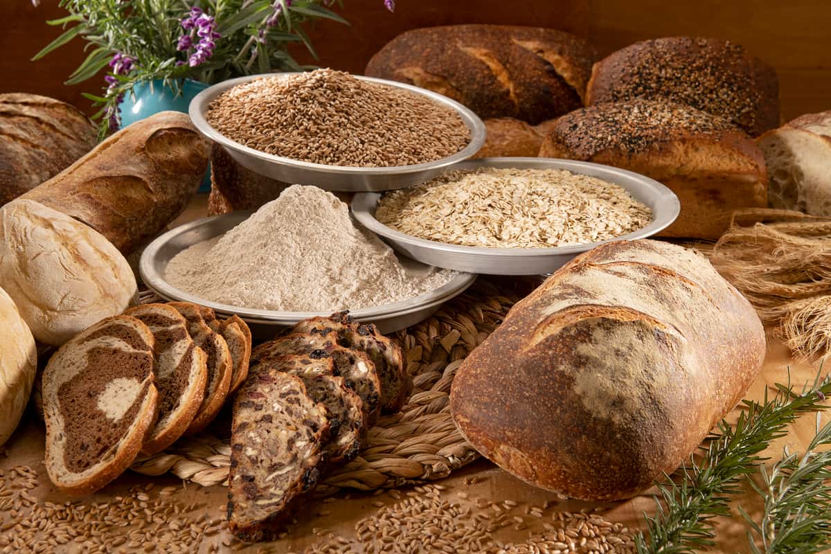 Bowls of whole grains and flours along with baked breads