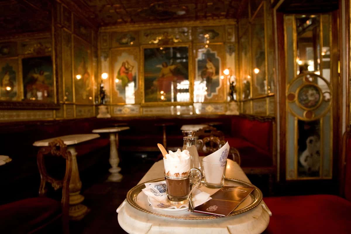 Platter of coffee and desserts inside a golden accented interior of a cafe in Venice Italy