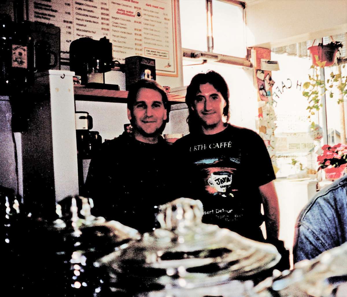 Two men stand in middle of photo inside caffe