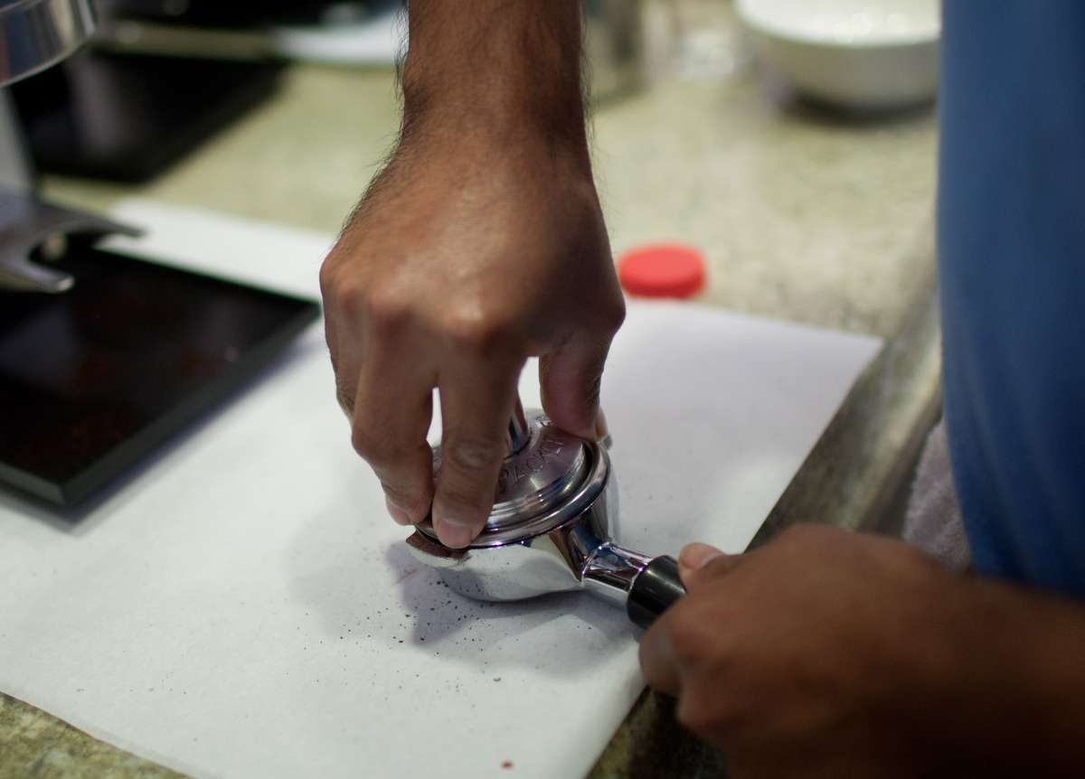 Barista packs ground coffee into filter