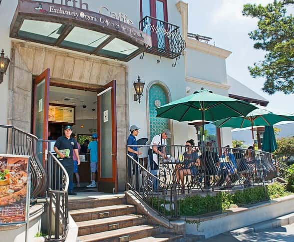 Day time view exterior of Urth Caffe Santa Monica patio with umbrellas, servers, guests