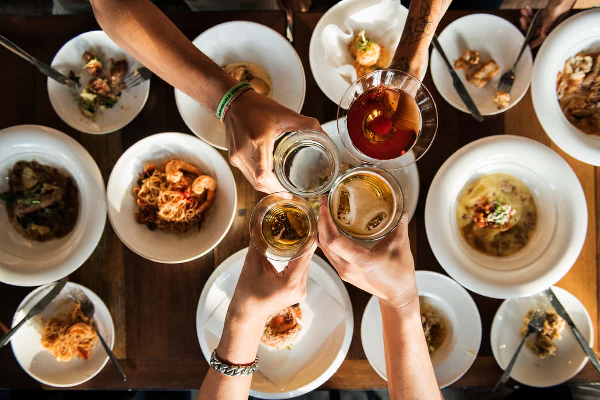 Group toasting with drinks over a table of plated meals