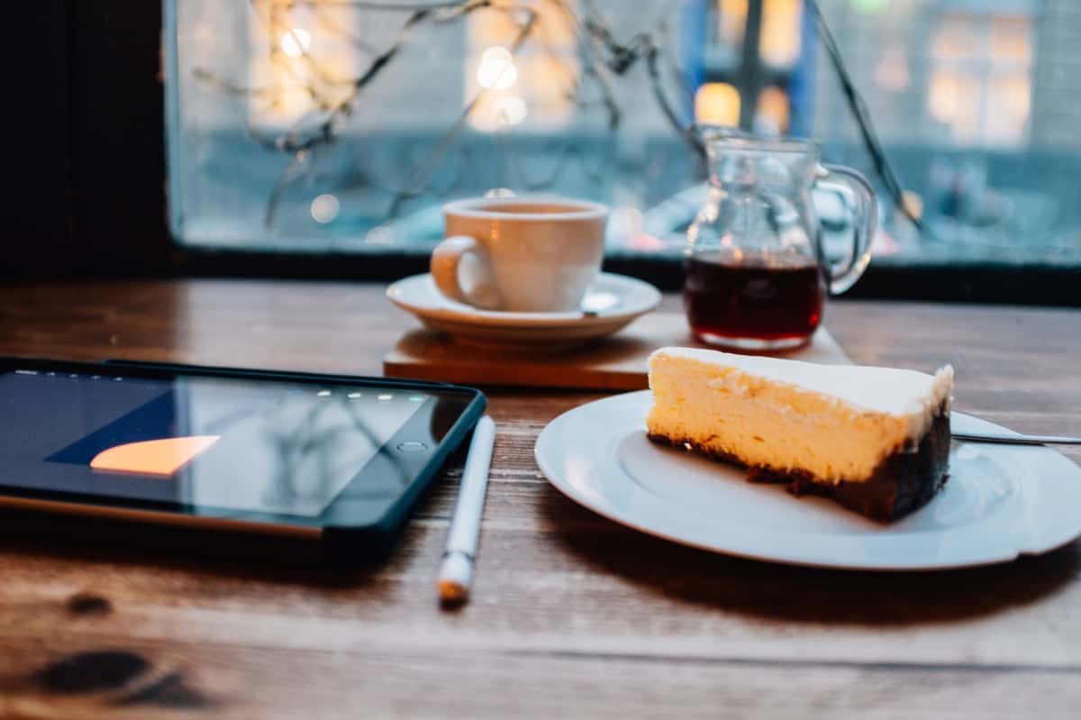 Cake at table with coffee, pen and tablet