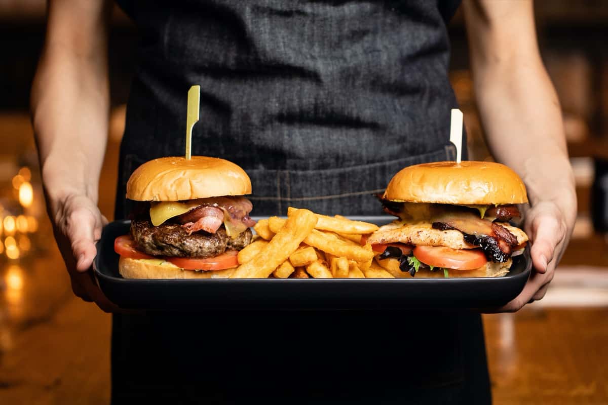Two burgers and fries carried on a serving tray