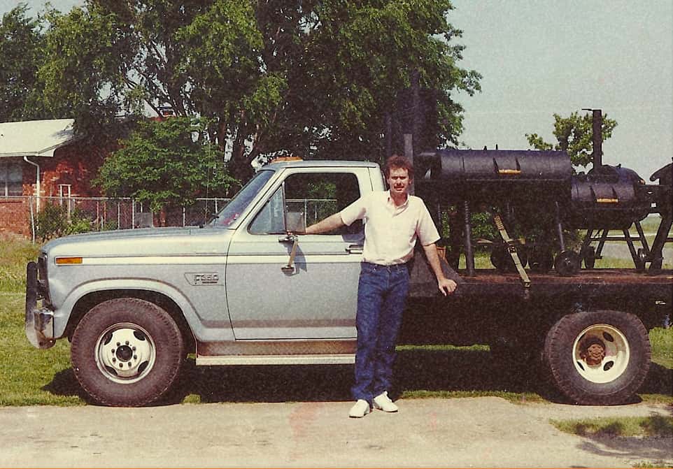 Joe standing in front of a white truck with smokers in the flat bed
