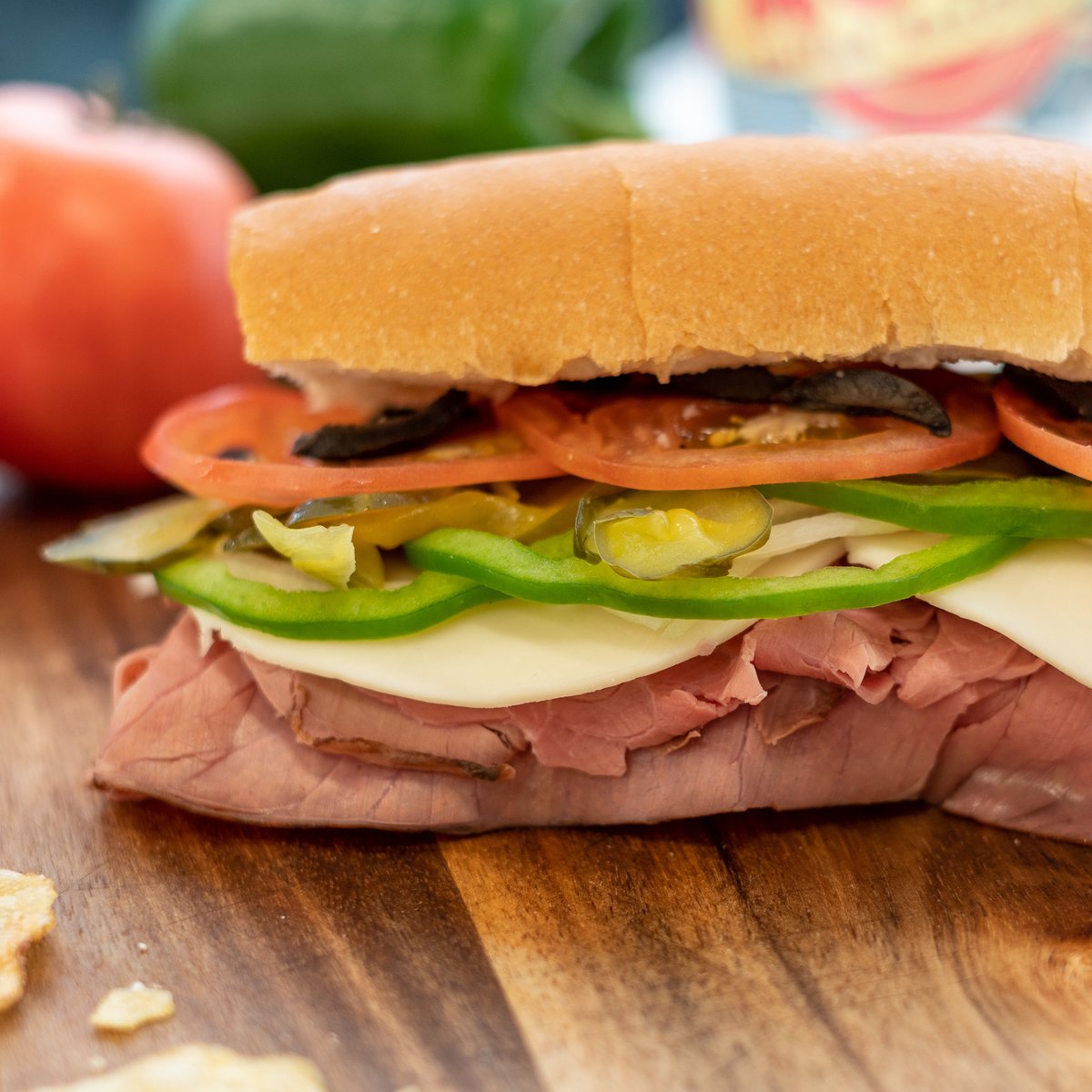 Sub sandwich with meat, peppers, onions, pickles, and tomatoes