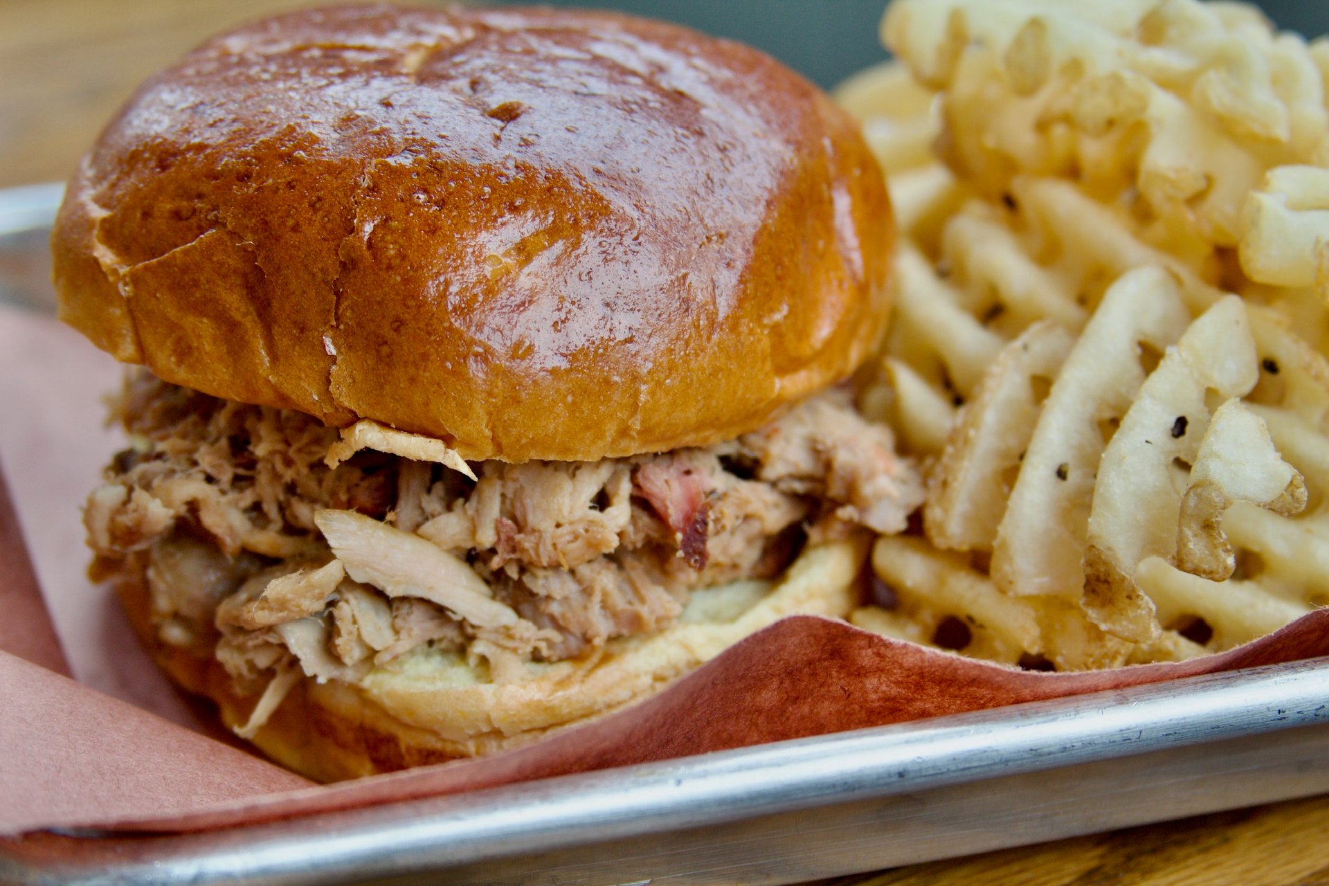 Pulled pork sandwich with a side of waffle fries.