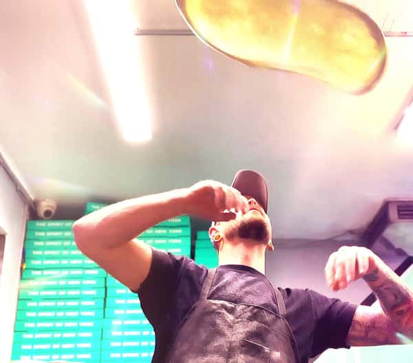 Cook tossing pizza dough