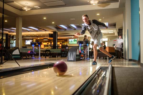 Kid throwing a bowling ball down a lane