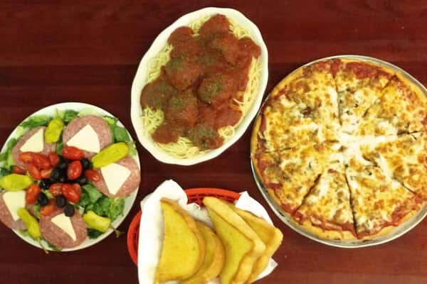 family meal with salad, spaghetti and meatballs, pizza and bread