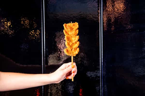 Person holding up a kebab of meat