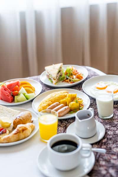 Various plates of fruit, eggs, sausage and other breakfast eats