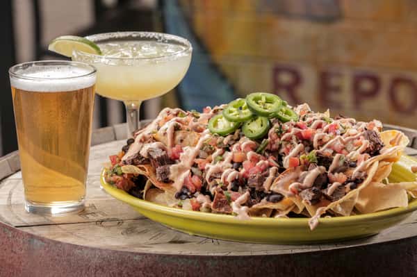nachos made with homemade chips topped with melted cheddar cheese, black beans, pico de gallo, chipotle crema, and jalapenos. Served along side with a cold beer and Cien-A-Rita.