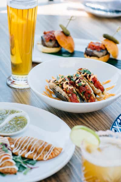 Multiple different menu items plated with a beer