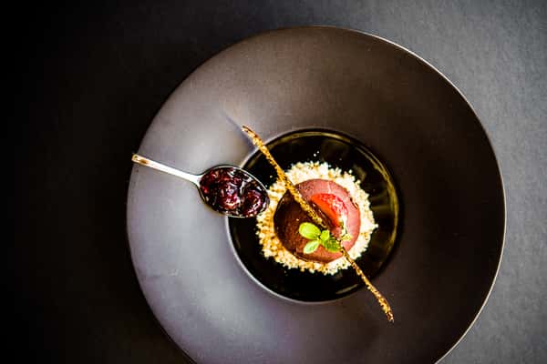 Chocolate Mousse: Delectable chocolate mousse on a bed of crushed cashew nuts served over blue and black berry sauce.