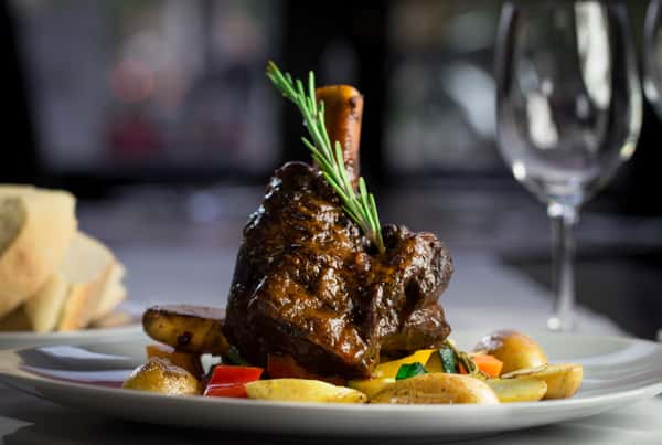 Lamb Shank: Slow braised lamb shank in red wine, garlic and rosemary, served with potatoes and mixed vegetables