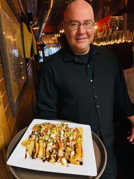 man chef holding loaded fries